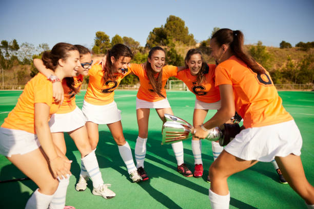 Teammates raise a gleaming trophy high in the air, a moment of sheer celebration following their tournament win.