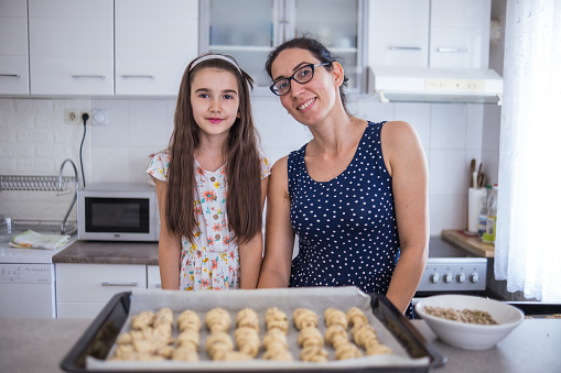 Happy little girl making croissants with her mother