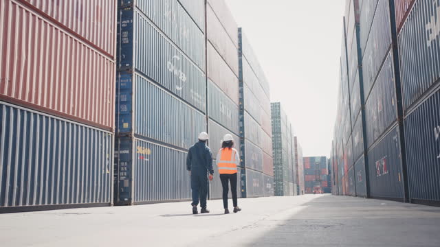 Engineers Holding walking through Cargo Containers In Shipping Container Yard.
