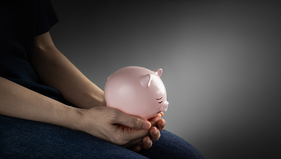 Finanacial crisis Concepts. a Depressed Person Holding a Sad Face Piggy Bank in the Gloomy Room. Mental Health Affected by Recession and Loss of Savings
