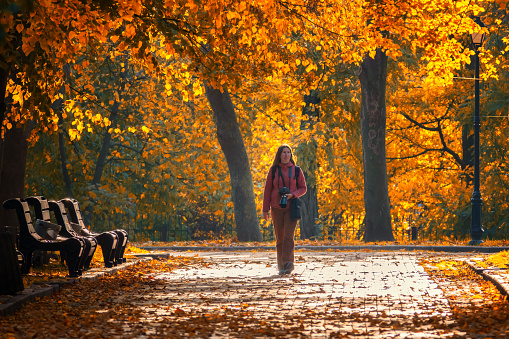 Woman photographer with photo camera in the sunny autumn park