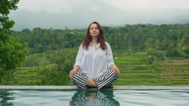 Woman doing yoga and meditation near the pool
