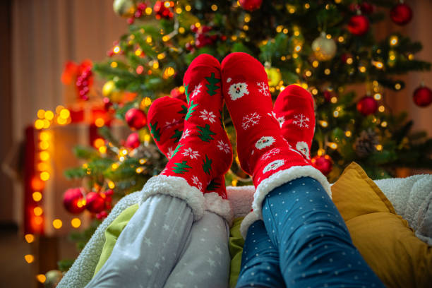 istock Feet wearing red woolen christmas socks next to Christmas tree 1652530410