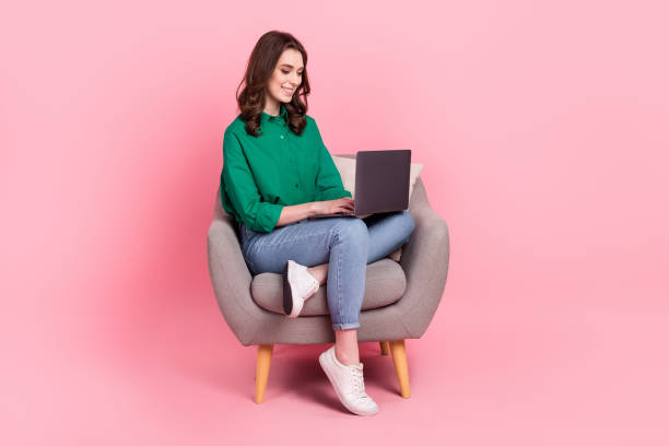 Full size photo of cheerful lovely girl sit comfy chair use wireless netbook isolated on pink color background stock photo