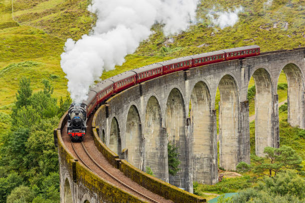 Famous steam training passing over a curved viaduct at Glenfinnan in the Scottish Highlands Famous steam training passing over a curved viaduct at Glenfinnan in the Scottish Highlands glenfinnan monument stock pictures, royalty-free photos & images