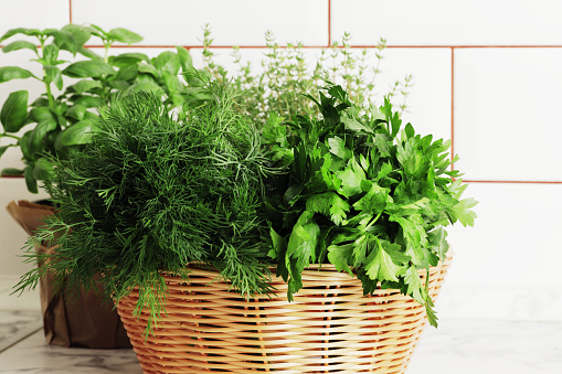 A basket full of fresh herbs on the kitchen table.