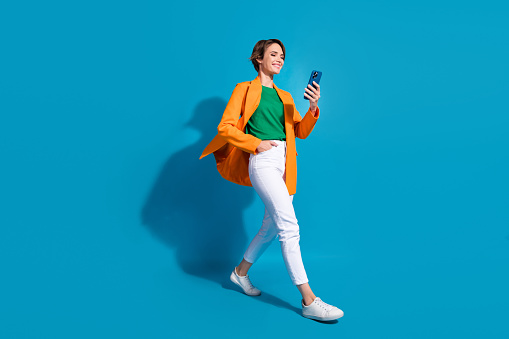 Full body size cadre of young optimistic project manager nice woman student communicating phone chat isolated on blue color background.