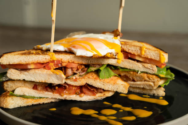 istock Club sandwich with grilled chicken, fried eggs, vegetables and cheddar cheese dip 1652578131