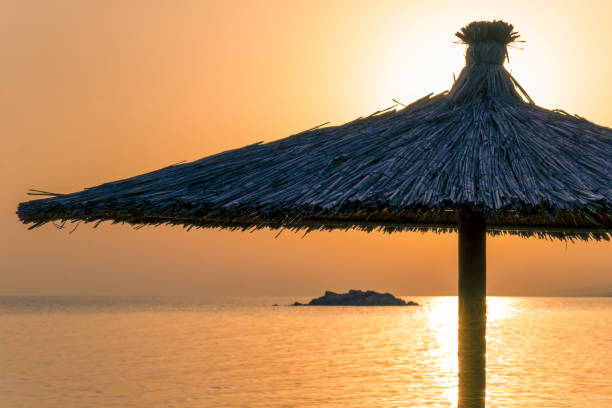 istock Orange sea and sky, beach umbrella at sunset 1652578260