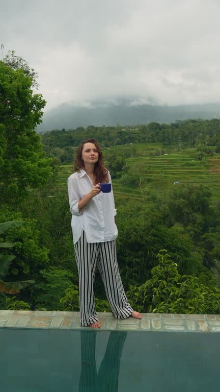 Woman drinking coffee in the morning near the pool on Bali