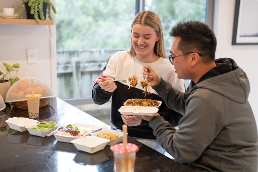 young couple enjoying takeaway food at home