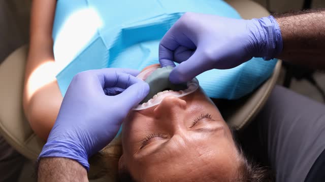 Dentist tries on dental sample for installing veneer