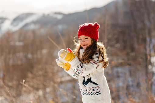 Playful girl running on the snow and having winter activities in nature