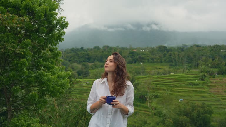 Woman drinking coffee in the morning near the pool on Bali