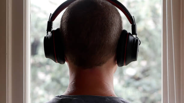 A Man Wearing His Headphones while Looking at the Rain from the Window