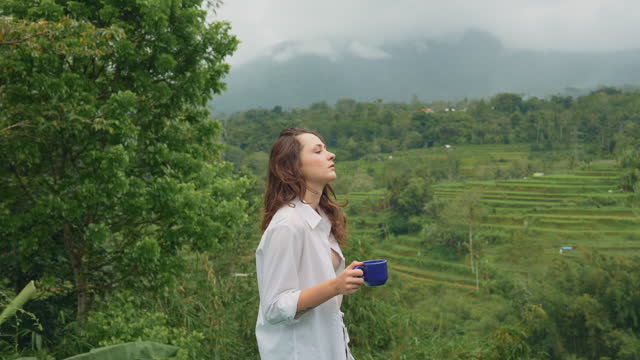 Woman drinking coffee in the morning near the pool on Bali