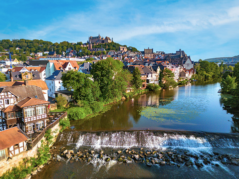drone view on historic Marburg over Lahn river at blue summer morning with weir in the foreground and castle in the background