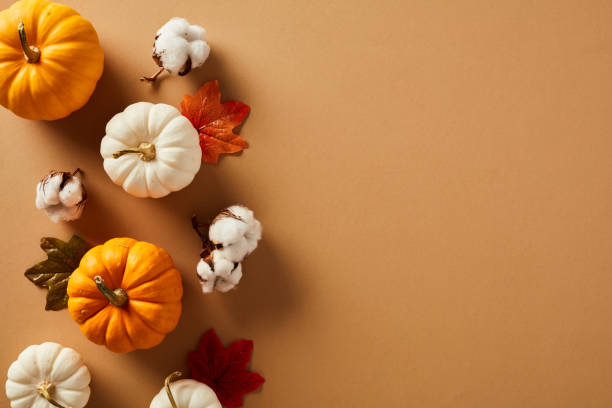 istock Flat lay composition with ripe pumpkins, cotton, maple leaves on brown background. Happy Thanksgiving day greeting card template. Autumn, fall concept. 1652719105