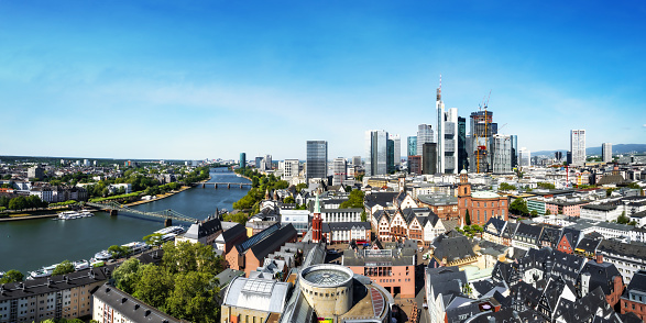 panoramic view over the roofs of Frankfurt city with modern skyline in the background and historic town in the foreground under blue sky, stitched image