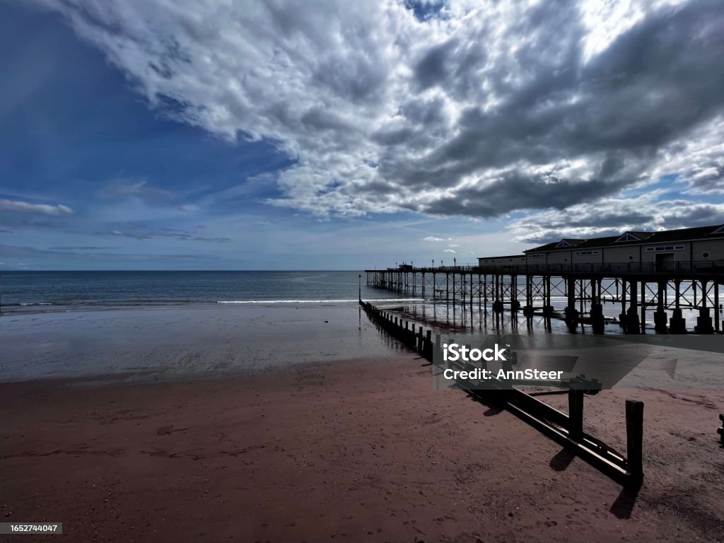 Cloudy sky over Teignmouth Deserted Teignmouth beach with atmospheric sky, pier and groynes Architecture Stock Photo
