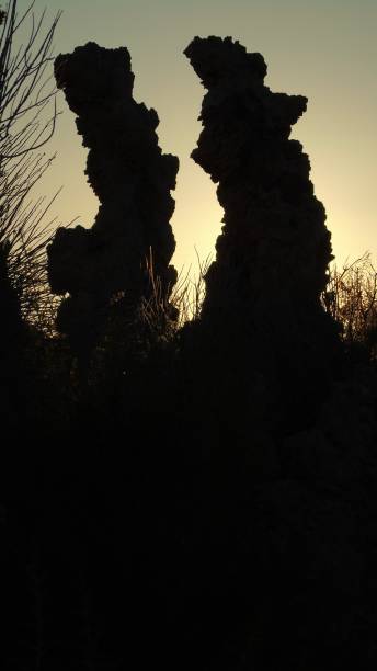 two curved monolith tufas of mono lake are in silhouette at dawn. - mono county imagens e fotografias de stock
