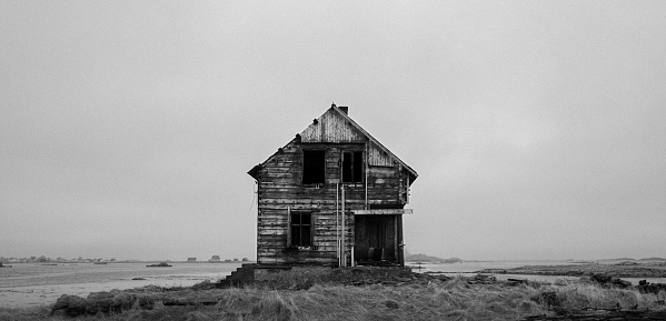 An isolated derelict house isolated on the desolate prairie with an arid grassland in the foreground
