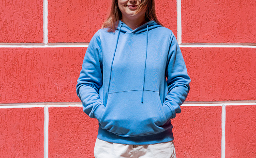 Smiling young woman in blue purple hoodie on red background copy space mockup friendly