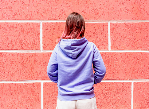 rear view of woman in blue purple hoodie with red hair on red background copy space mockup friendly