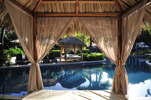 View of a pool from a canopy bed in a tropical setting