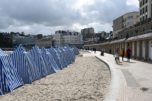 Dinard, Brittany, France, August 30, 2023 - Blue and white striped beach huts on the city beach (Plage de l'Ecluse) of Dinard, Brittany.