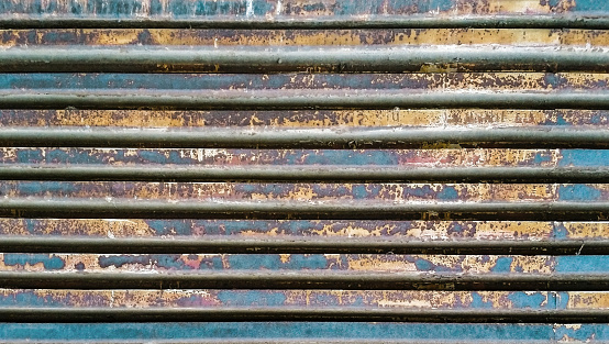 High resolution image of an obsolete weathered, corroded, rusty steel stripe screen panel surface detail, background grunge texture.