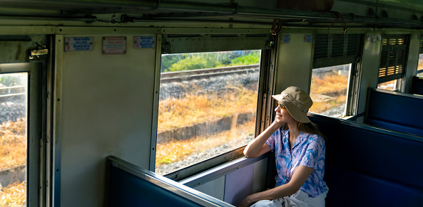 Caucasian woman tourist travel in Thailand on local train. Attractive woman tourist travel on railroad transportation on summer holiday vacations.
