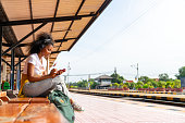 African woman traveler waiting for train at local railroad station.