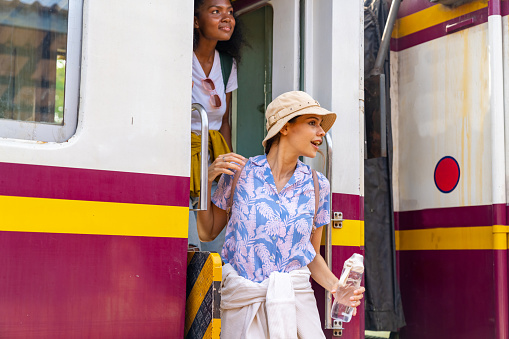 Woman tourist meet local tour guide at train station. Diversity woman friends enjoy outdoor lifestyle travel to Ayutthaya province in Thailand by railroad transportation on summer holiday vacations.
