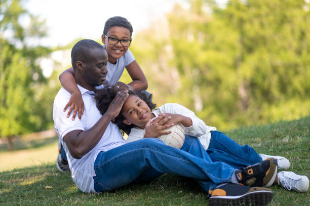 istock Dad and two kids sitting on the grass in the park 1652805752