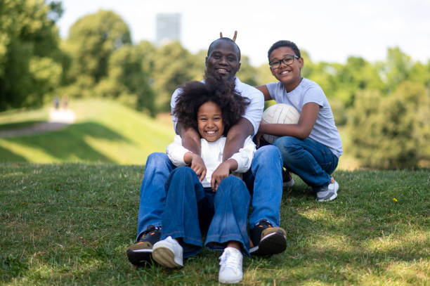 istock Dad and two kids sitting on the grass in the park 1652805790