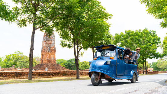 Group of Diversity people travel Ayutthaya Province in Thailand on summer holiday vacations. Man and woman friends tourist travel architecture and old ruin temple famous place by Auto rickshaw or tuk tuk taxi.