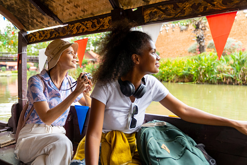 Group of Diversity people traveler travel floating market by traditional wooden boat in canal during travel Ayutthaya Province in Thailand on summer holiday vacation.