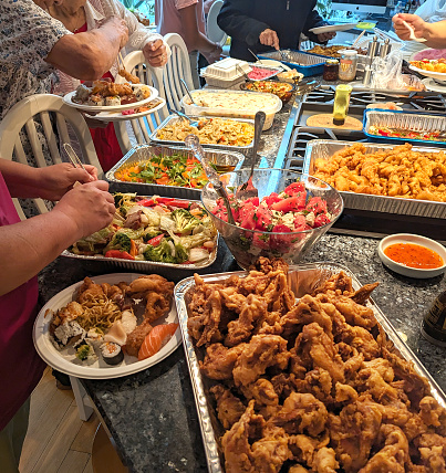 Senior family members select homemade and takeout food at a buffet-style dinner in a Canadian home.
