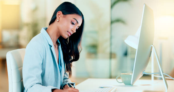istock Businesswoman typing out financial reports while working on a computer in her office. Female accountant managing finances and doing bookkeeping using software to compile data and writing notes 1652819619