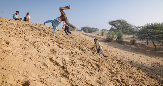 Group of happy Indian children jumping from a sand dune - desert village, Thar Desert, Rajasthan, India.