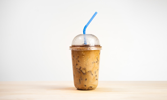 Iced caff mocha or coffee latte in takeaway cup on wooden table. coffee package for takeaway, Cold beverage product.