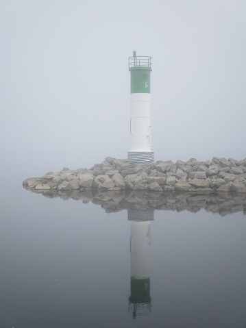 lighthouse reflected in water on foogy morning