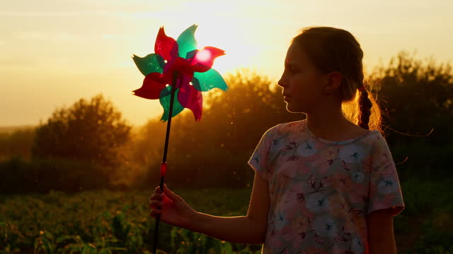 Silhouette of child girl holding wind toy