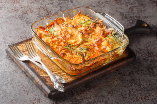 Roasted sweet potato gratin with cheese, eggs and rosemary close-up in a glass baking dish. Horizontal stock photo