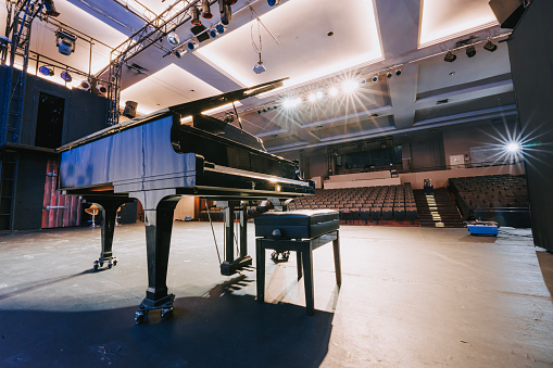 grand piano on stage facing empty theatre auditorium