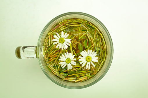 Glass mug with chamomile tea standing on the table. The concept of phototherapy.
