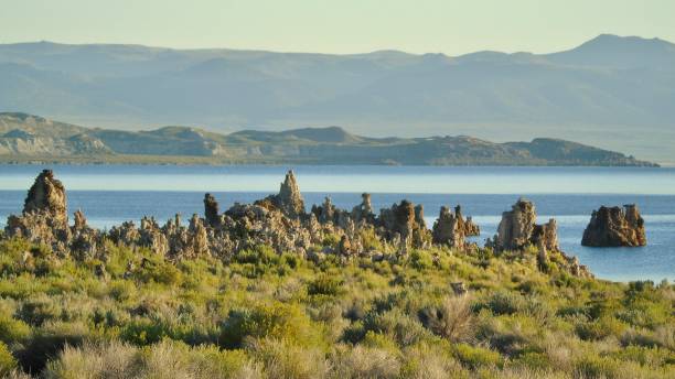 brown tufa rock formations contrast the waters of mono lake in the shadow of the sierra nevada range. - mono county imagens e fotografias de stock