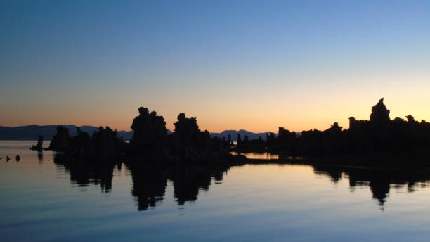 a rising sun creates a pink background for silhouetted tufa rock formations at mono lake. - mono county imagens e fotografias de stock