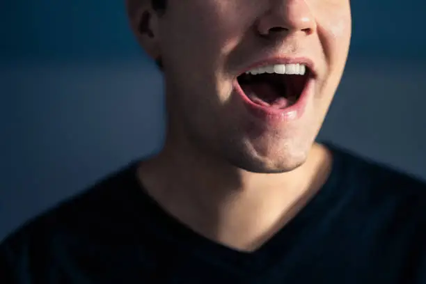 Photo of Sing, talk or speak. Singer mouth open. Man with loud sound of voice. Pronunciation in language education, articulation exercise or vocal lesson. Song in music studio. Speech or karaoke.